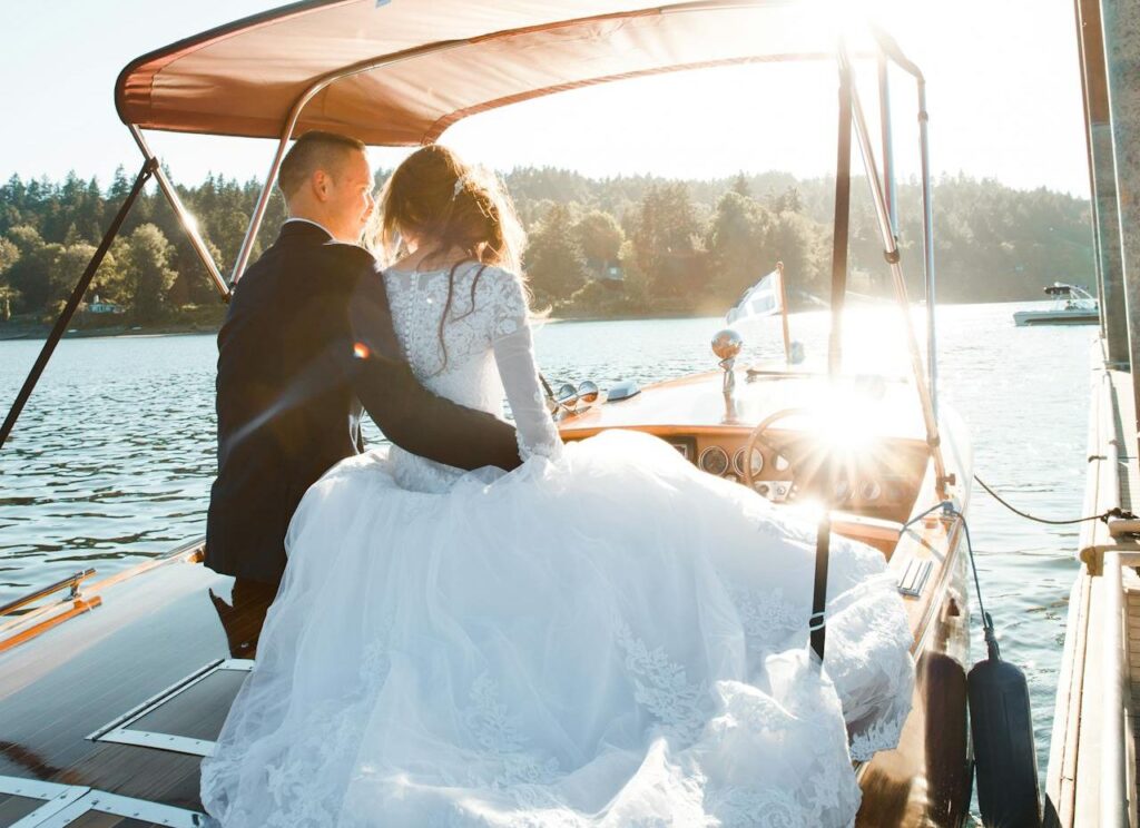 A bride and groom on a boat in the water, showcasing a boho wedding dress in NZ. A picturesque moment of love and celebration