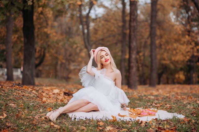 Woman in white dress sitting on ground in fall, short wedding dress nz