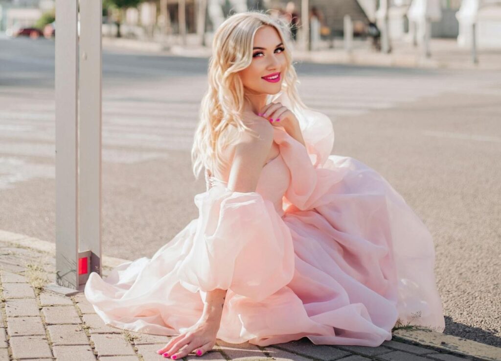 A woman in a pink dress sitting on the street